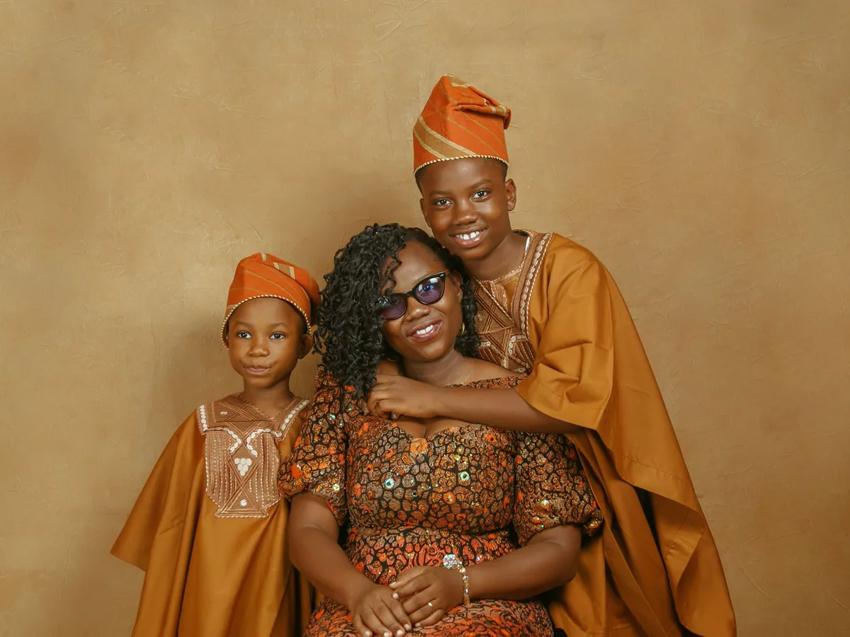 A Nigerian family in colourful traditional Yoruba attire, smiling together.