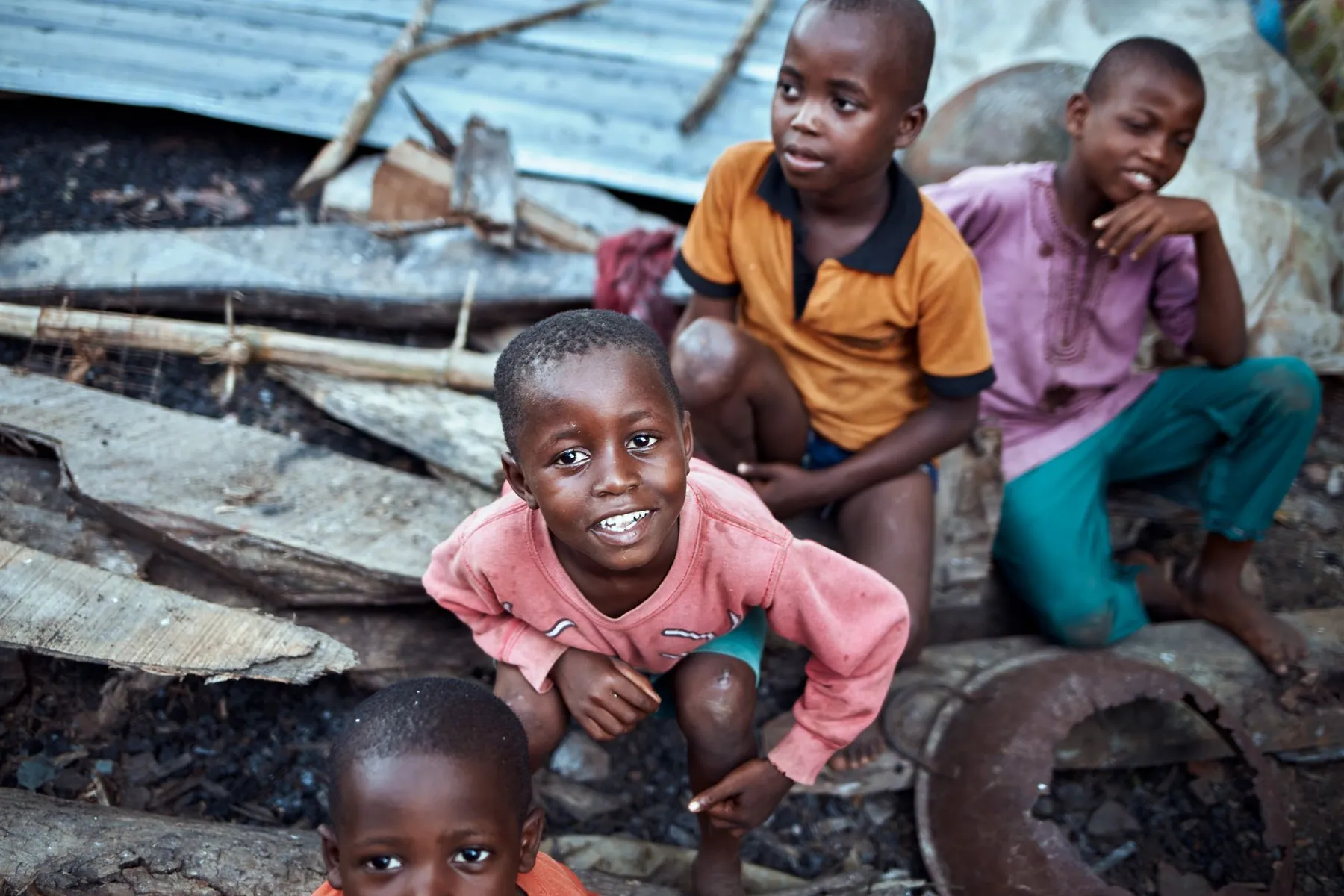 Four young Nigerian children outdoors, one smiling directly at the camera.