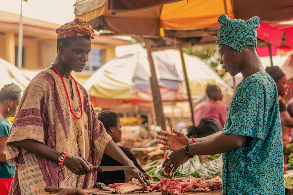 A market trader at her stall surrounded by goods.